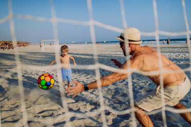 Vater mit seinem Sohn beim Fußballspielen am Strand. - HPIF09798