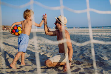 Vater mit seinem Sohn beim Fußballspielen am Strand. - HPIF09799