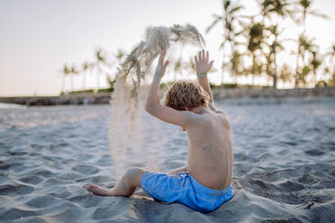 Rückansicht eines kleinen verspielten Jungen, der mit Sand am Strand spielt. - HPIF09802