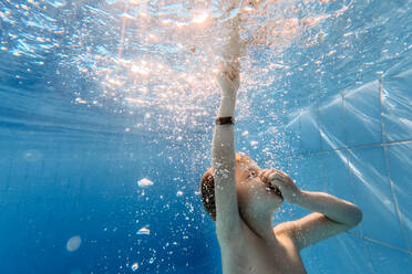 Kleiner Junge taucht mit geschlossenen Augen in einem Schwimmbad. - HPIF09804