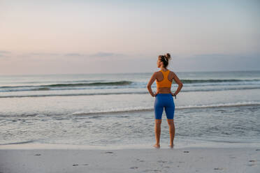 Rückansicht einer jungen, sportlichen Frau am Strand. - HPIF09824