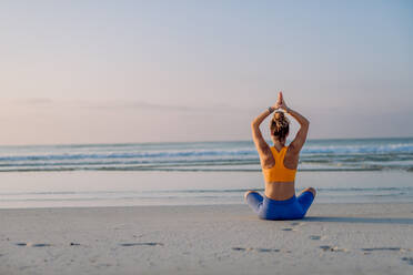 Sports woman doing yoga along the beach – Jacob Lund Photography