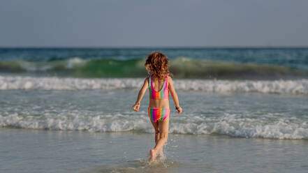 Little girl in swimsuit running in the sea, enjoying summer holiday. - HPIF09839