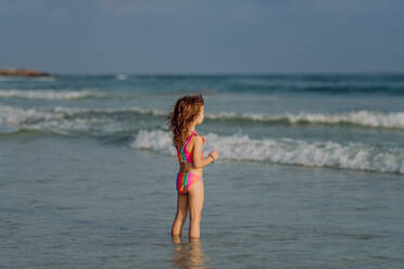 Little girl in swimsuit standing in the sea, enjoying summer holiday. - HPIF09840