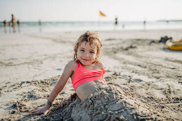 Kleines Mädchen, das sich im Sand räkelt und den exotischen Sommerurlaub am Meer genießt. - HPIF09856