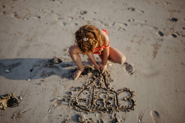Kleines Mädchen malt im Sand am Strand während des Sommerurlaubs. - HPIF09859