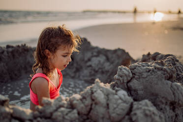 Kleines Mädchen spielt am Strand und gräbt ein Loch in den Sand. - HPIF09860