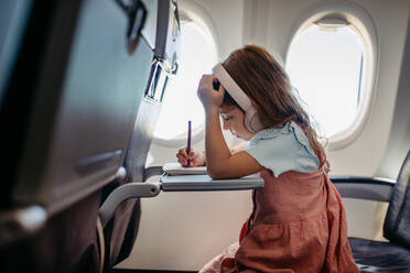 Little girl in an airplane drawing and listening music. - HPIF09865