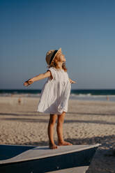Kleines Mädchen in Sommerkleid und Hut genießt die Zeit am Meer während der Sommerferien. - HPIF09868