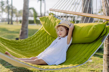 Kleines Mädchen mit Strohhut liegt in einer Hängematte und genießt den exotischen Sommerurlaub. - HPIF09870
