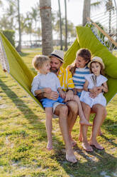 Junge Familie mit kleinen Kindern, die ihren Urlaub in einem exotischen Land genießen und in einer Hängematte liegen. - HPIF09872