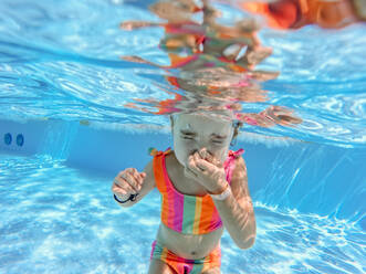 Kleines Mädchen im Badeanzug beim Tauchen in einem Schwimmbad. - HPIF09884