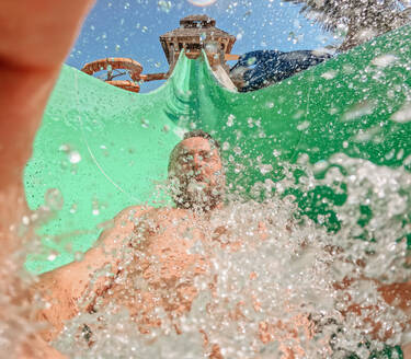 Nahaufnahme eines Mannes auf einer Wasserrutsche, der den Sommer genießt. - HPIF09886