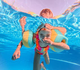 Little girl in swimsuit diving in a swimming pool. - HPIF09887
