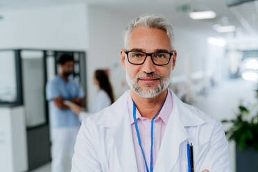 Porträt eines reifen Arztes in einem Krankenhauskorridor. - HPIF09896