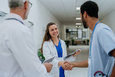 Nahaufnahme von Ärzten beim Händeschütteln in einem Krankenhausflur. - HPIF09906