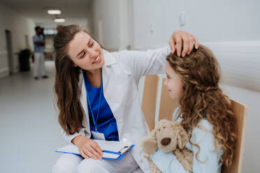 Junger Arzt spielt mit seinem kleinen Patienten auf dem Flur der Kinderklinik. - HPIF09921