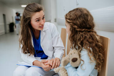 Junger Arzt im Gespräch mit seinem kleinen Patienten auf dem Flur der Kinderklinik. - HPIF09923