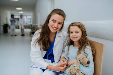Porträt eines jungen Arztes mit seinem kleinen Patienten auf dem Flur der Kinderheilkunde. - HPIF09925