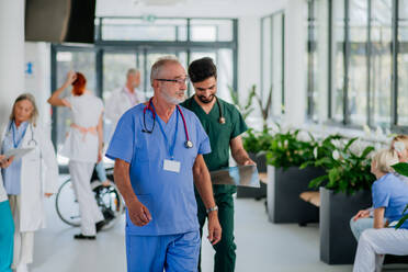 Junge Ärzte auf dem Krankenhausflur bei der täglichen Untersuchung von Patienten. - HPIF09996