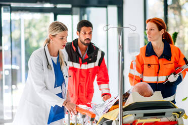 Junge Ärztin, die sich um einen Patienten aus einem Rettungswagen kümmert. - HPIF10013