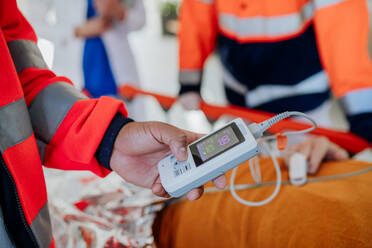 Nahaufnahme von Rettungskräften, die einen Patienten aus dem Krankenwagen versorgen und ein Oximeter überprüfen. - HPIF10020