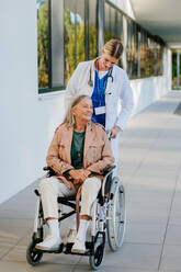 Junge Ärztin, die sich um eine ältere Frau in einem Rollstuhl kümmert. - HPIF10038
