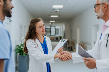 Nahaufnahme von Ärzten beim Händeschütteln in einem Krankenhausflur. - HPIF10048