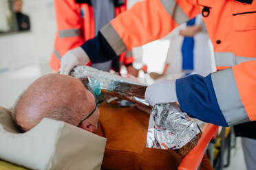 Rettungskräfte versorgen einen Patienten aus einem Krankenwagen, Nahaufnahme. - HPIF10075