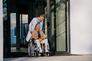 Junge Ärztin, die sich um eine ältere Frau in einem Rollstuhl kümmert. - HPIF10086