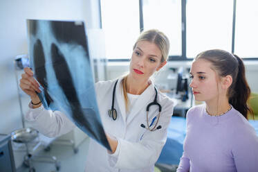 Junge Ärztin zeigt dem Patienten ein Röntgenbild der Lunge. - HPIF10125