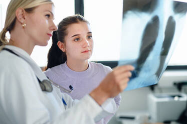Junge Ärztin zeigt dem Patienten ein Röntgenbild der Lunge. - HPIF10126