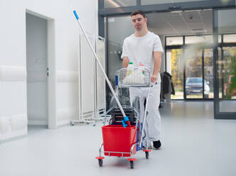 Young man with down syndrome working in hospital as cleaner. Concpet of integration people with disability into society. - HPIF10150