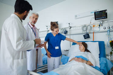 Eine ältere Frau liegt nach der Chemotherapie im Krankenhauszimmer, eine Krankenschwester prüft ihre Temperatur. - HPIF10276
