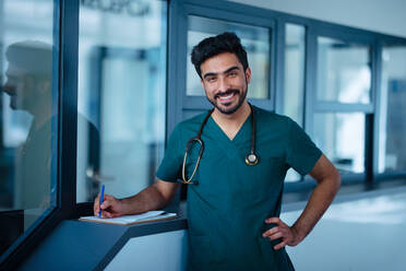 Porträt eines glücklichen jungen Arztes in einem Krankenhauszimmer. - HPIF10316