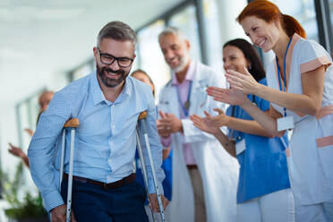 Medical staff clapping to patient who recovered from a serious accident. - HPIF10326