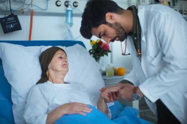 Ein junger Arzt aus dem Nahen Osten untersucht einen krebskranken Patienten in einem Krankenhaus. - HPIF10332
