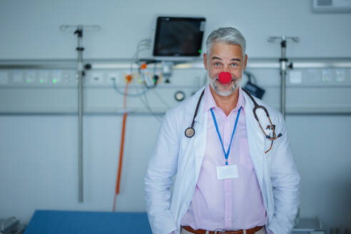 Porträt eines glücklichen Arztes mit roter Clownsnase in einem Krankenhauszimmer. - HPIF10341