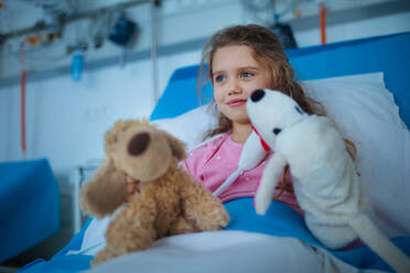 Porträt eines kleinen Mädchens in einem Krankenhauszimmer mit ihren Spielsachen. - HPIF10348