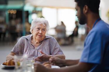 Caregiver having breakfast with his client at a cafe. - HPIF10364