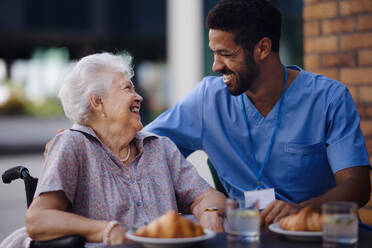 Caregiver having breakfast with his client at a cafe. - HPIF10367