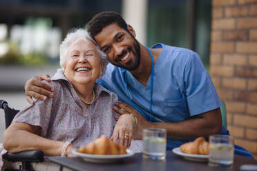 Caregiver having breakfast with his client at a cafe. - HPIF10368