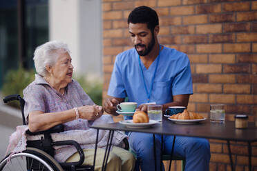 Caregiver having breakfast with his client at a cafe. - HPIF10369