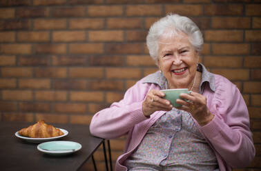 Glückliche ältere Frau beim Frühstück in einem Stadtcafé. - HPIF10395