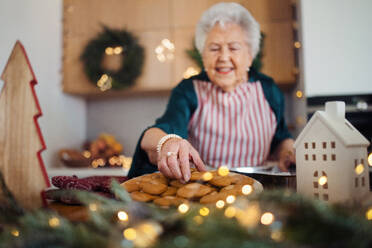 Glückliche ältere Frau, die zu Hause Weihnachtskuchen backt. - HPIF10455