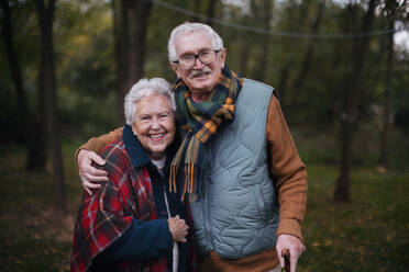Porträt eines älteren Paares, das zusammen in der herbstlichen Natur spazieren geht. - HPIF10527