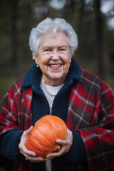 Seniorin mit Kürbissen in herbstlicher Natur. - HPIF10532