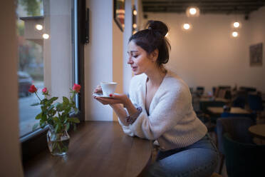 Junge Frau genießt eine Tasse Kaffee, sitzt in einem Café. - HPIF10544