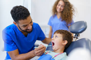 Ein kleiner Junge sitzt auf einem Zahnarztstuhl während einer zahnärztlichen Untersuchung. - HPIF10568