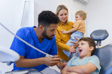 Kleiner unglücklicher Junge sitzt während der Untersuchung auf dem Zahnarztstuhl. - HPIF10571